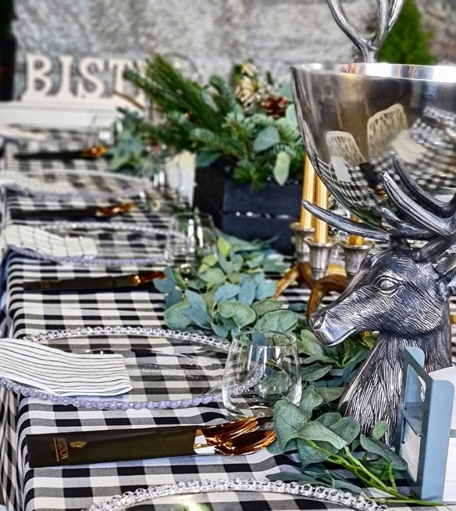 A Christmas table set with a checked tablecloth, plates and greenery