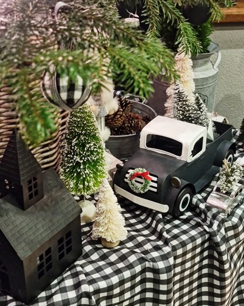 A Christmas display with pine cones and a miniature car on a table