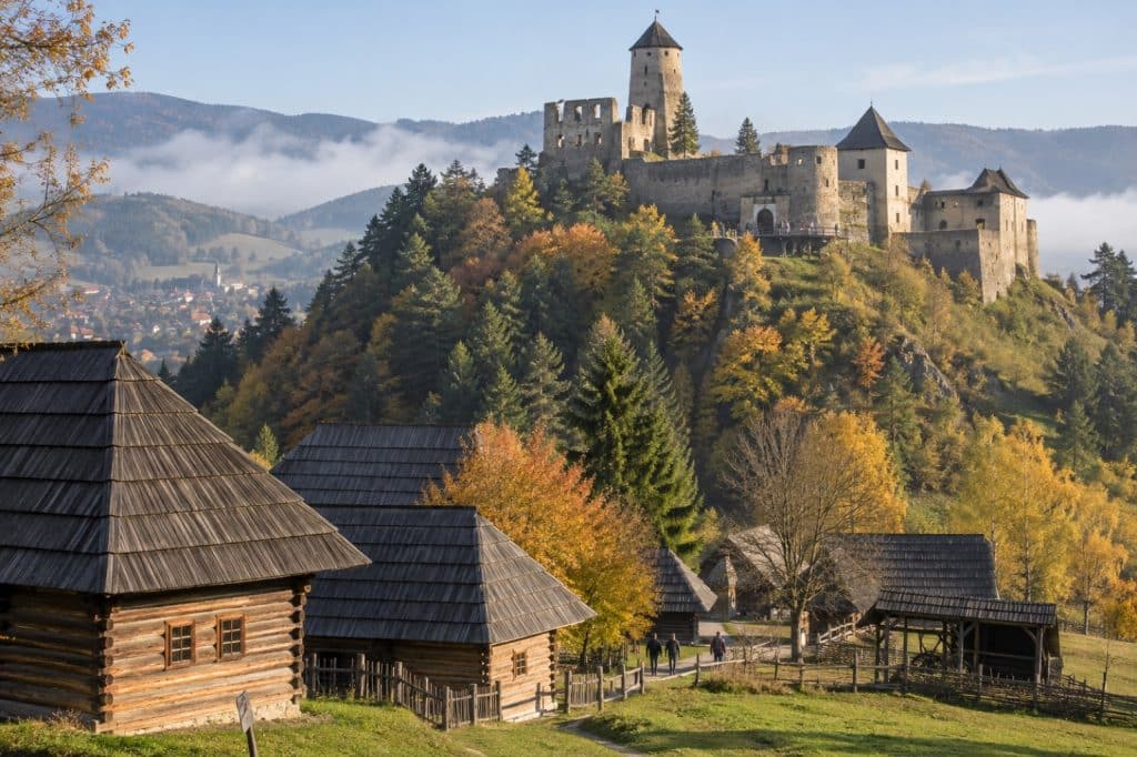 Ľubovňa Castle on a hill and wooden open-air museum buildings in autumn